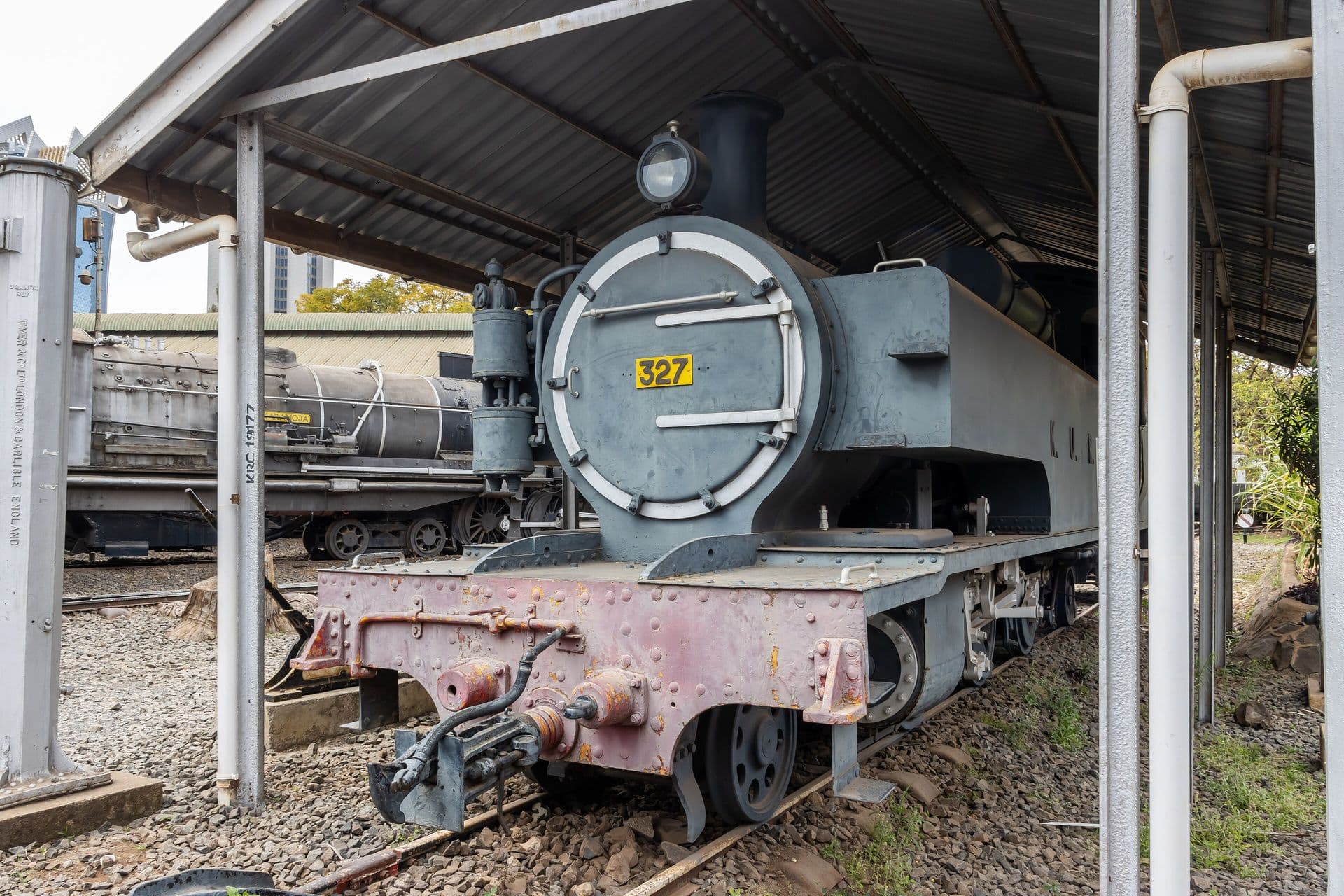 A grey steam locomotive numbered 327 under a shelter at the Nairobi Railway Museum