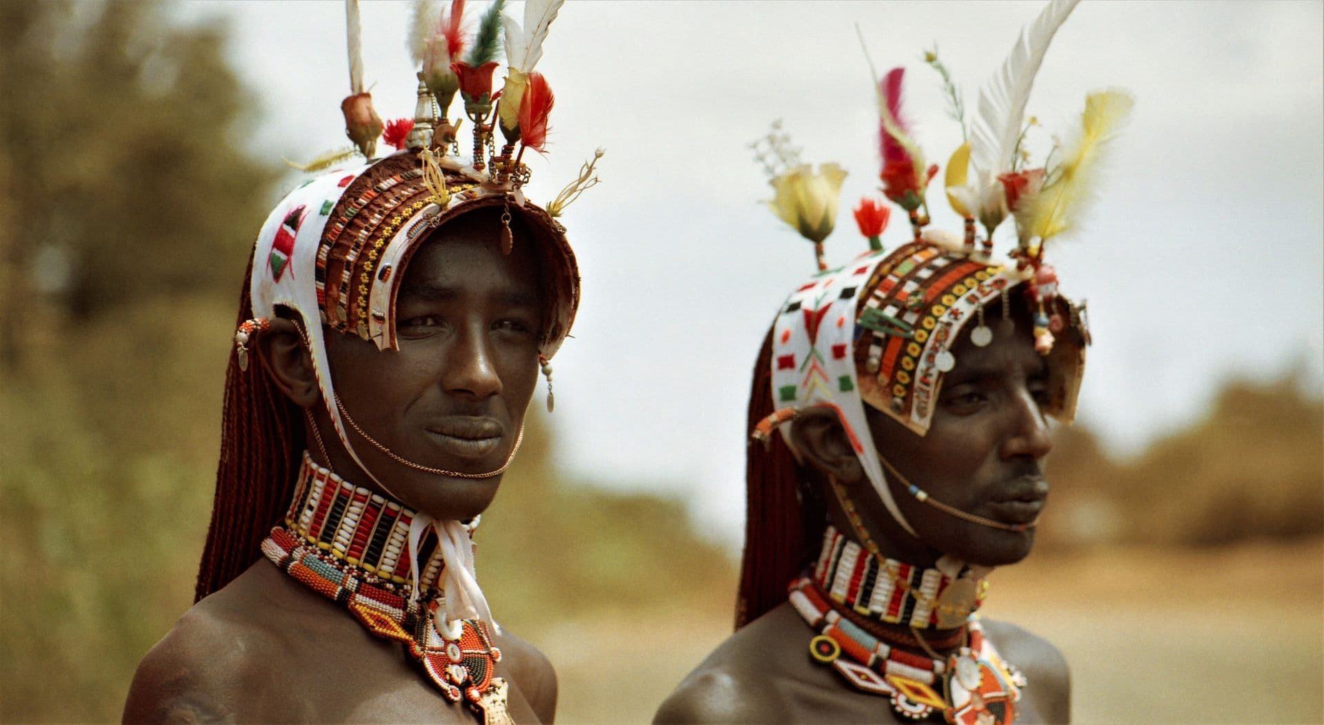 Two young Samburu men wearing beaded and feathered headdresses