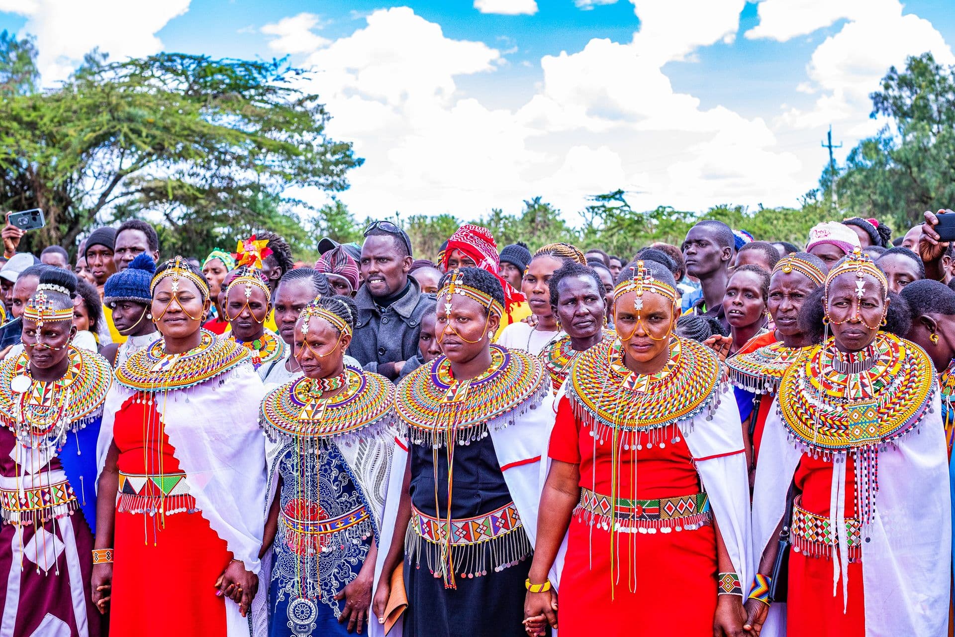 A large crowd of Samburu women in beaded collars and red and white cloth at the Maralal festival