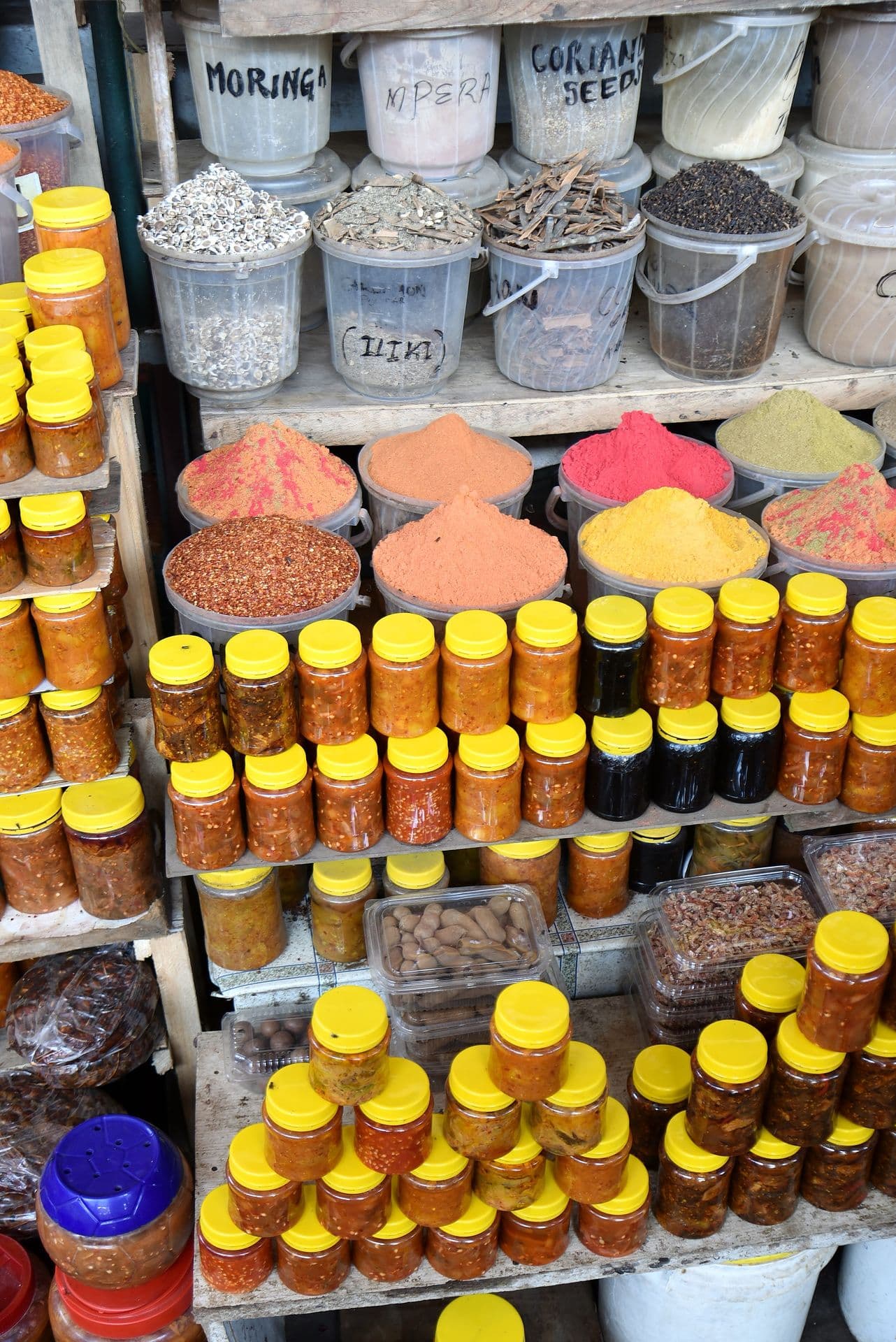 Shelves of spices, powders and yellow-capped jars at a stall in Mackinnon Market, Mombasa