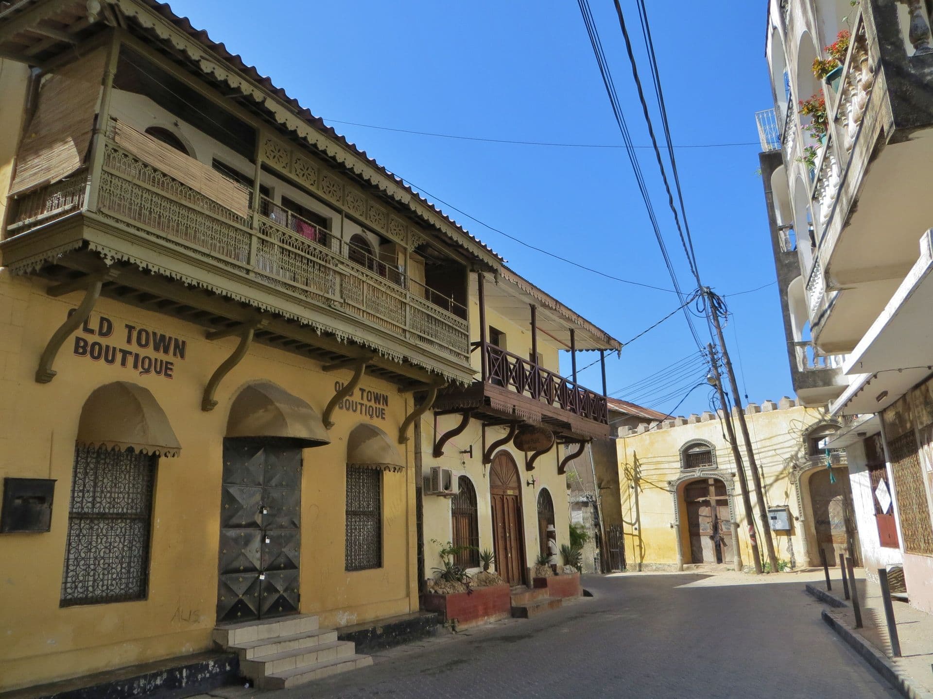 A yellow building with a carved wooden balcony on a quiet street in Mombasa Old Town