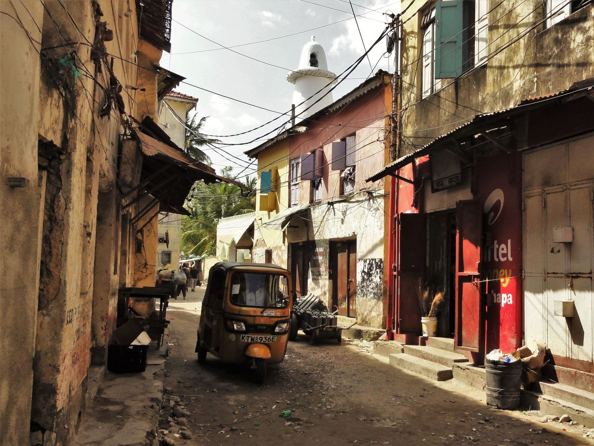 A tuk-tuk on a narrow street of old multi-storey buildings in Mombasa Old Town