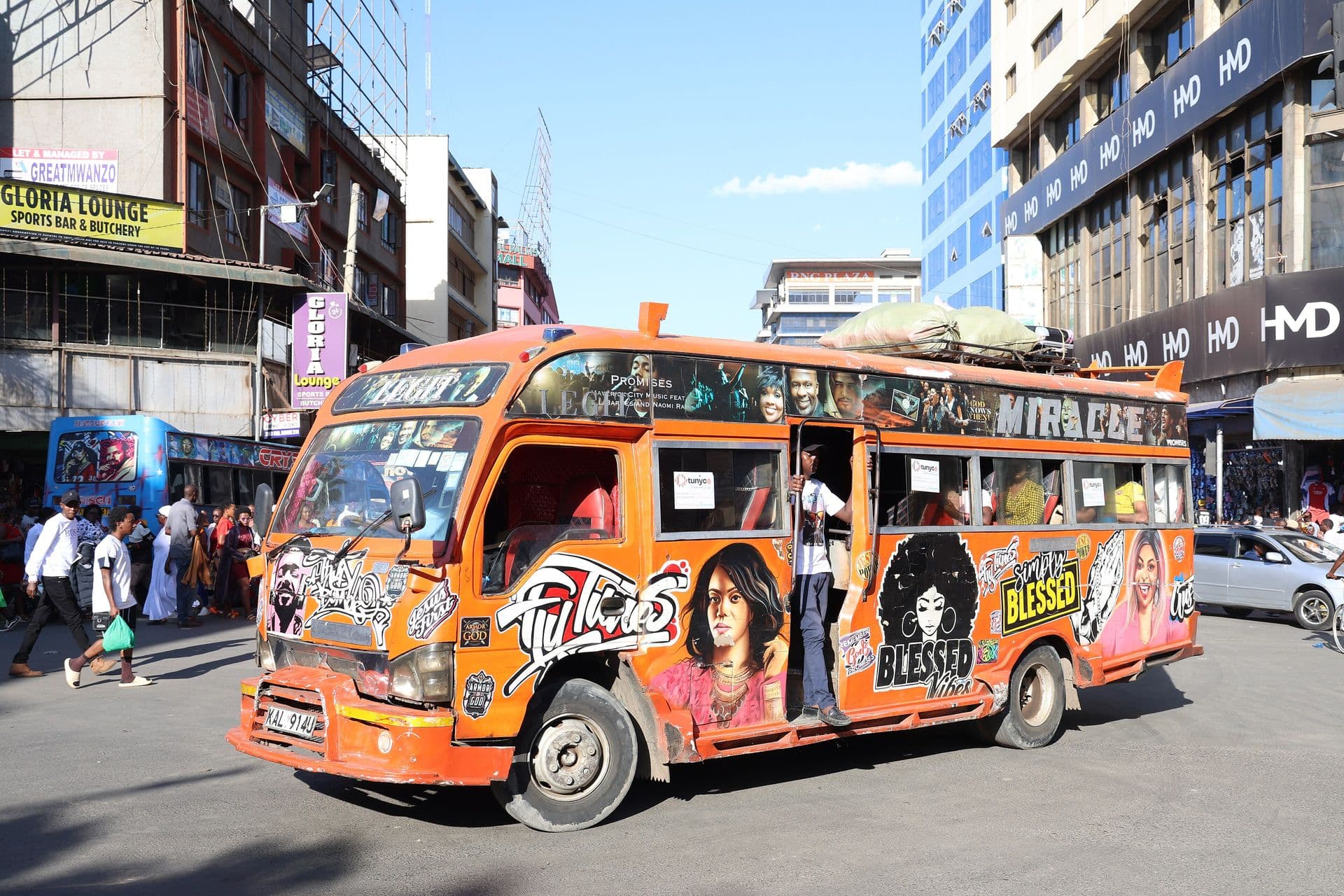 A brightly painted orange matatu minibus on a busy Nairobi street